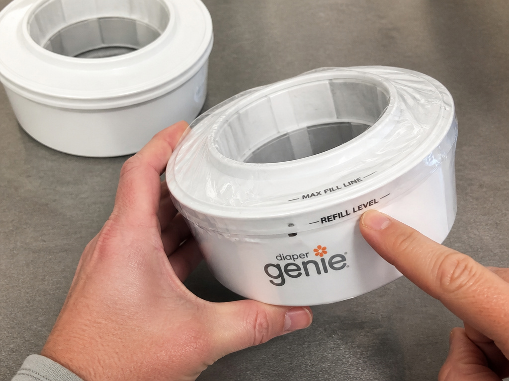 Close-up comparison of Diaper Genie refill cartridges with and without indicator lines.